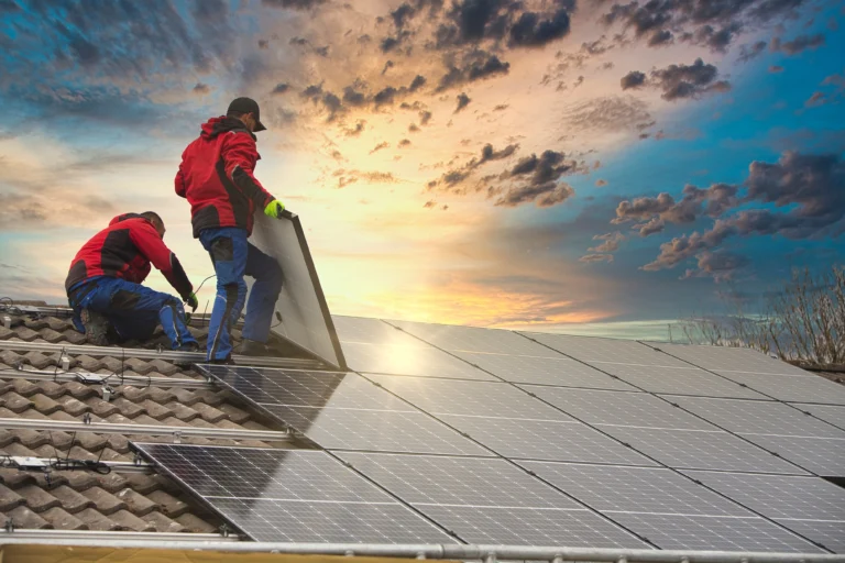 Arbeiter montieren Photovoltaikanlage auf einem Dach bei Sonnenuntergang